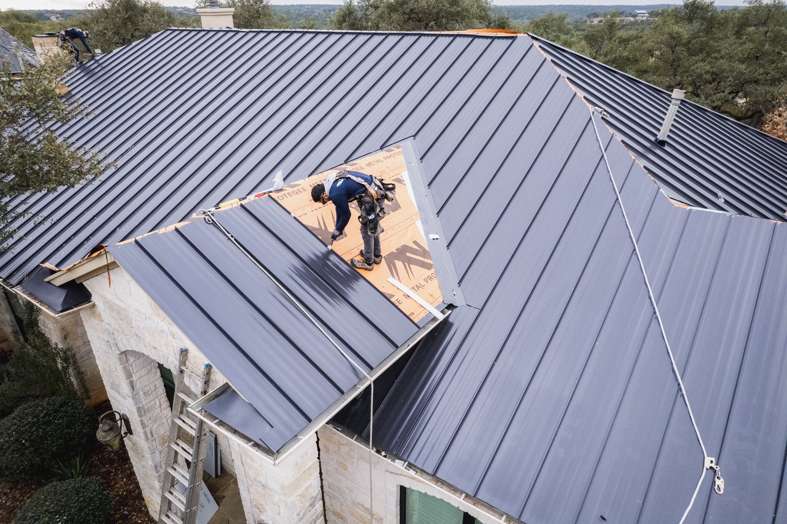 Standing seam metal roof installation in progress with Hill Country views